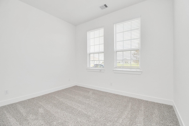 spare room featuring visible vents, light colored carpet, and baseboards