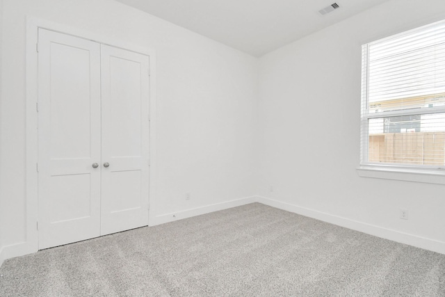 carpeted empty room featuring visible vents and baseboards