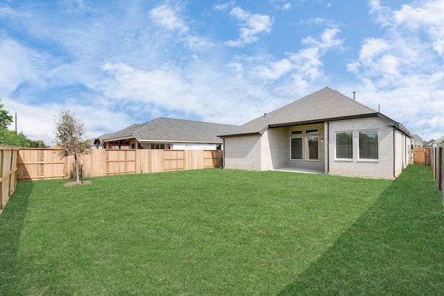 back of house featuring a lawn, brick siding, and a fenced backyard