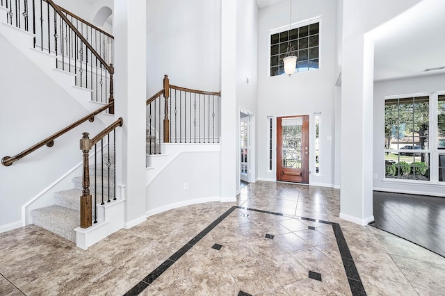 foyer entrance featuring stairs, visible vents, baseboards, and a towering ceiling