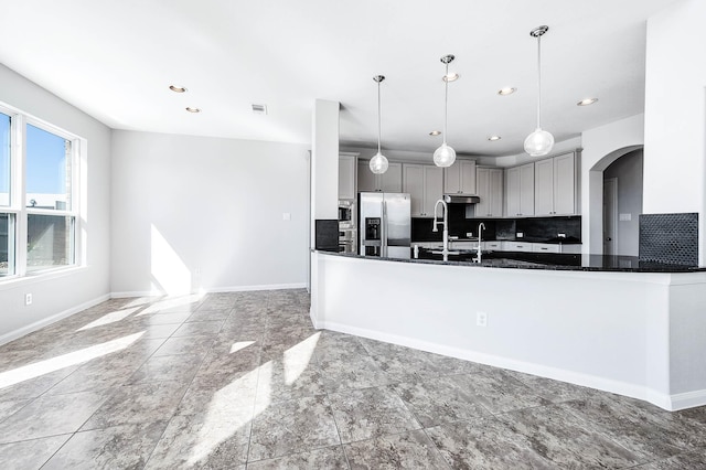 kitchen featuring dark countertops, tasteful backsplash, baseboards, gray cabinets, and appliances with stainless steel finishes