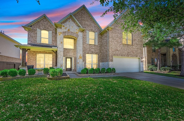 traditional home with a garage, a yard, stone siding, and driveway