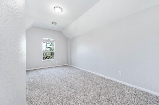 additional living space featuring carpet flooring, visible vents, baseboards, and lofted ceiling