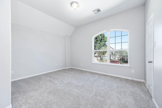 empty room featuring visible vents, baseboards, carpet, and vaulted ceiling