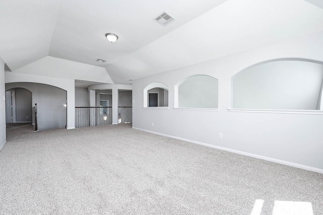 spare room with baseboards, visible vents, carpet floors, lofted ceiling, and arched walkways