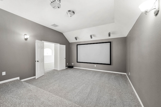 home theater room featuring lofted ceiling, carpet, and baseboards