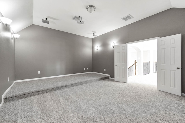 unfurnished room featuring visible vents, baseboards, carpet, and lofted ceiling