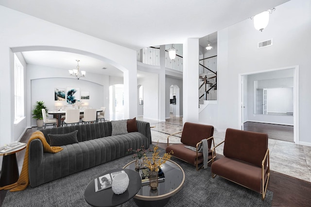 living area featuring visible vents, stairs, a towering ceiling, arched walkways, and a notable chandelier