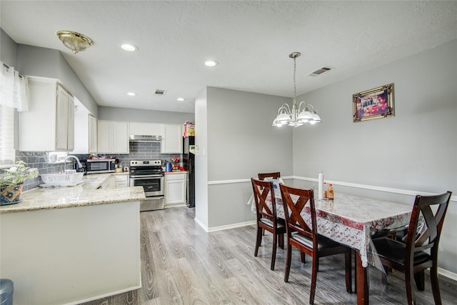 dining space featuring visible vents, baseboards, light wood-style flooring, and a chandelier