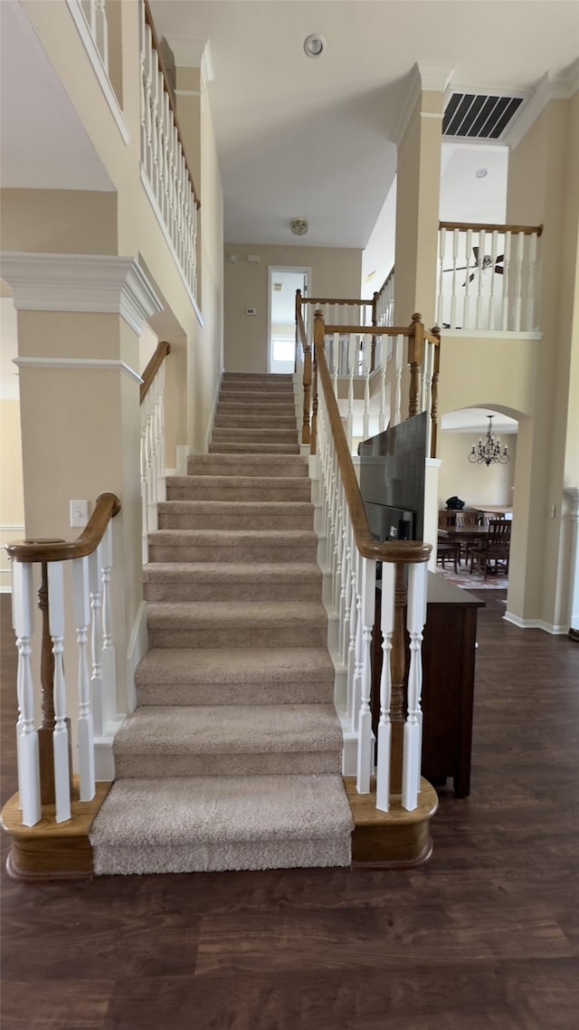 stairway featuring visible vents, crown molding, a high ceiling, and wood finished floors