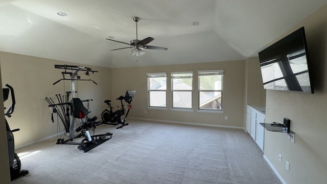 exercise room with vaulted ceiling, light colored carpet, baseboards, and ceiling fan