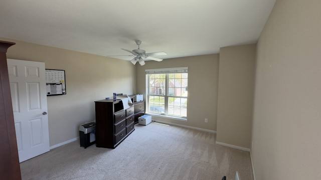 interior space featuring light colored carpet, a ceiling fan, and baseboards