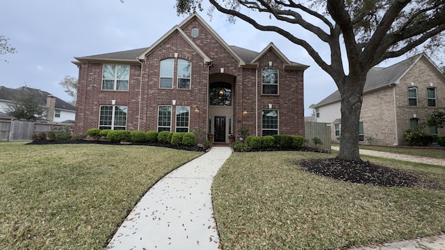 traditional home with brick siding, a front yard, and fence