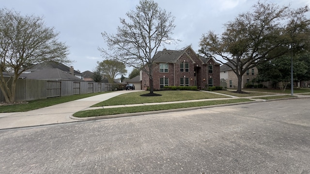 view of front facade featuring a front lawn, fence, concrete driveway, an attached garage, and brick siding