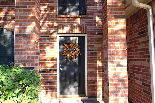 doorway to property featuring brick siding