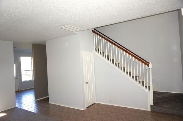 interior space featuring tile patterned floors, visible vents, a textured ceiling, stairway, and baseboards