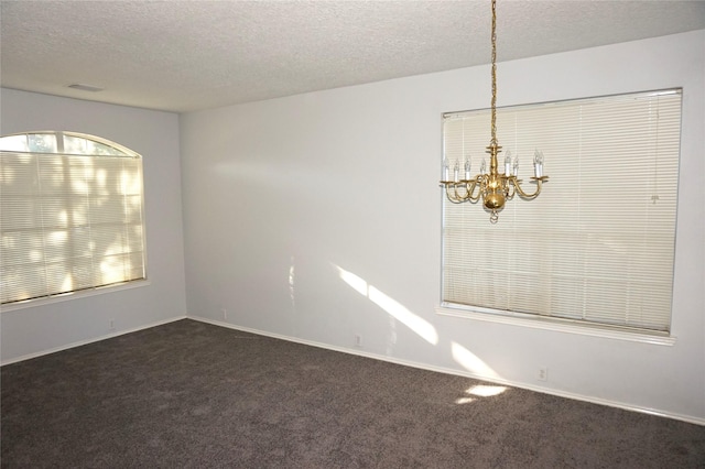 unfurnished room featuring baseboards, a textured ceiling, a chandelier, and dark carpet