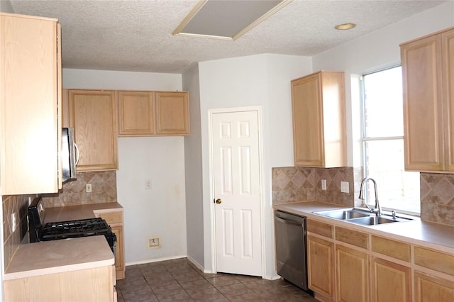 kitchen with light brown cabinets, a sink, light countertops, appliances with stainless steel finishes, and dark tile patterned floors