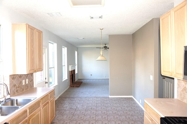 kitchen featuring light brown cabinetry, visible vents, backsplash, and a sink