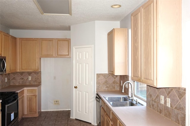 kitchen with a sink, dark tile patterned flooring, appliances with stainless steel finishes, and light countertops