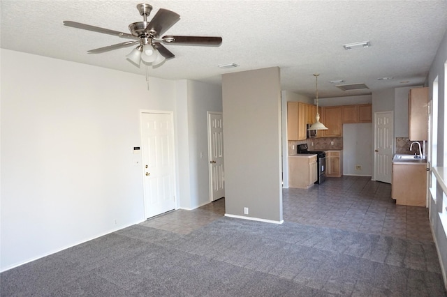 unfurnished living room featuring visible vents, dark carpet, ceiling fan, and a sink