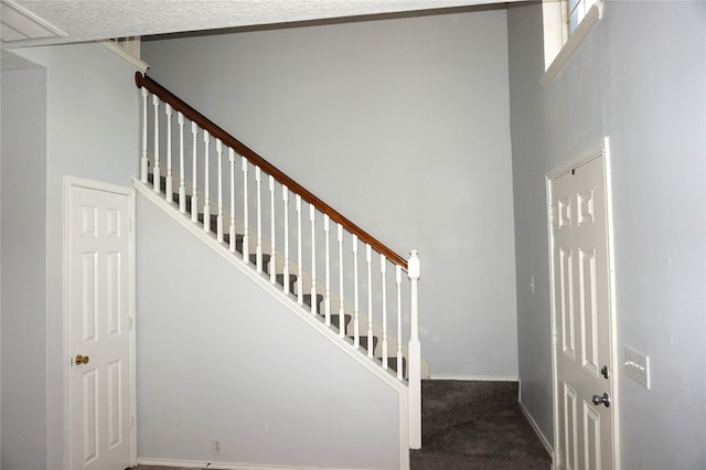 stairs with a high ceiling and carpet floors