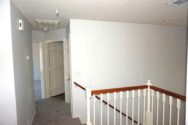 hallway featuring an upstairs landing, visible vents, and carpet