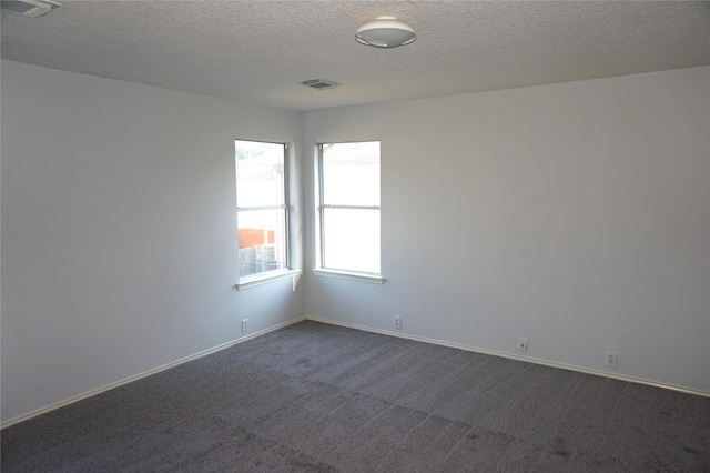 empty room featuring visible vents, baseboards, a textured ceiling, and dark carpet