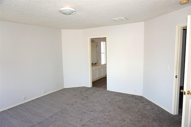 carpeted spare room with visible vents and a textured ceiling