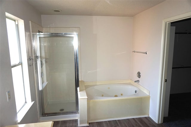 full bathroom with wood finished floors, a jetted tub, and a stall shower