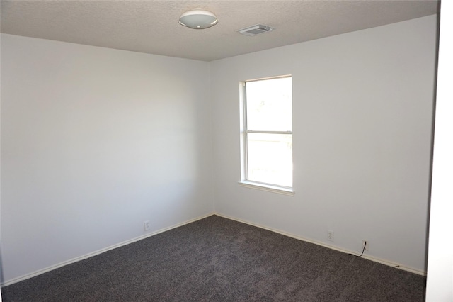 spare room with baseboards, visible vents, dark carpet, and a textured ceiling