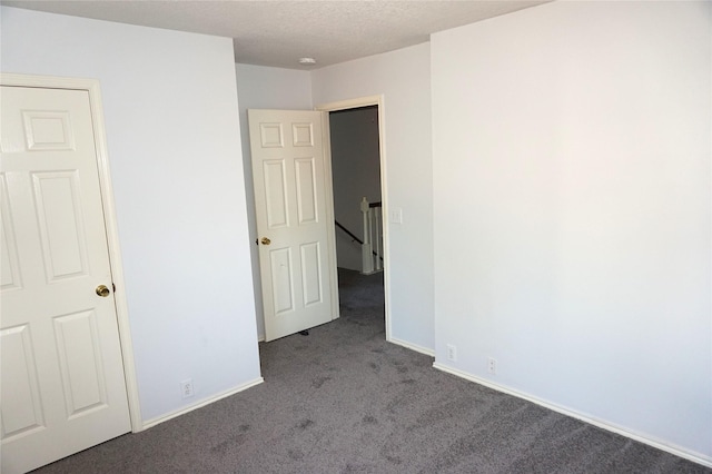 unfurnished bedroom with carpet flooring, a textured ceiling, and baseboards