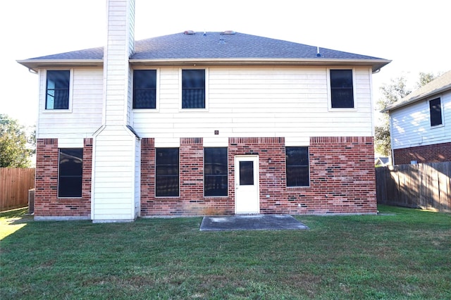 rear view of property with a patio, a lawn, brick siding, and a fenced backyard