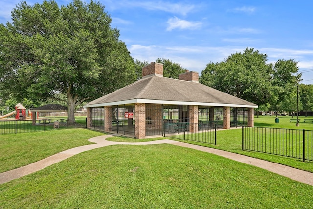 exterior space with playground community, a front lawn, brick siding, and a chimney