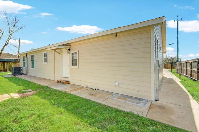 rear view of house featuring a patio, cooling unit, a yard, and fence