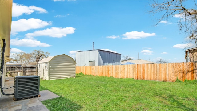 view of yard featuring a fenced backyard, central AC unit, a storage unit, and an outdoor structure