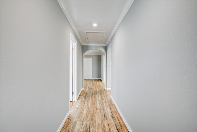 hallway with baseboards, arched walkways, light wood-style floors, and ornamental molding