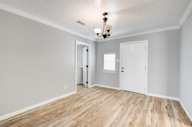 unfurnished room featuring visible vents, light wood-style flooring, a textured ceiling, crown molding, and a chandelier