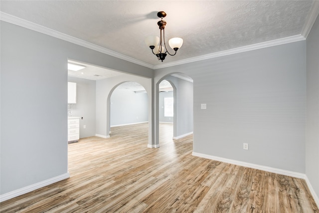 spare room with light wood-style flooring, baseboards, and arched walkways