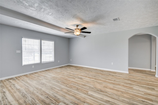 unfurnished room featuring baseboards, arched walkways, a ceiling fan, and light wood finished floors