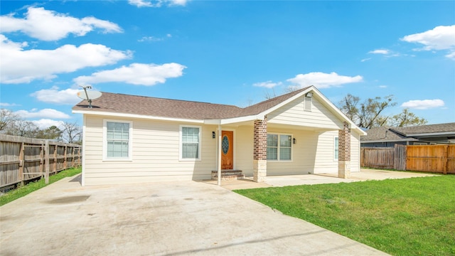 back of property featuring a yard, a patio area, roof with shingles, and fence