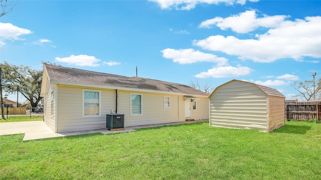 rear view of house featuring central air condition unit, a lawn, and fence