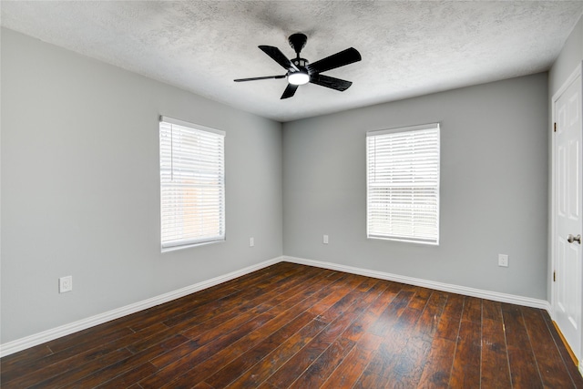 spare room with a wealth of natural light, dark wood-style floors, baseboards, and a ceiling fan