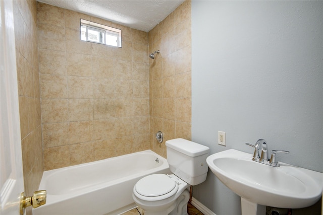 bathroom with a sink, shower / bath combination, toilet, and a textured ceiling