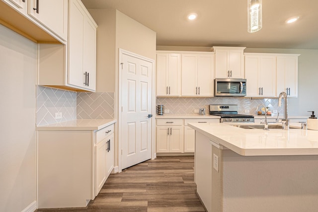 kitchen with stainless steel appliances, wood finished floors, white cabinets, and light countertops