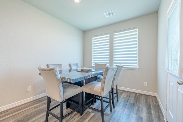 dining space with wood finished floors, visible vents, and baseboards