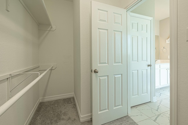 walk in closet with marble finish floor