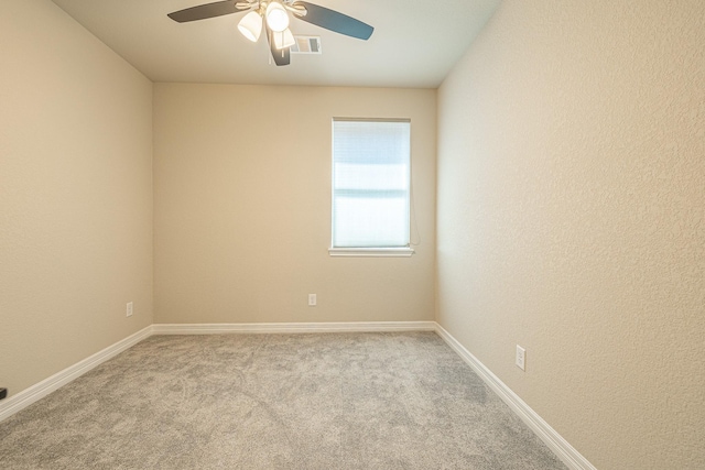 carpeted spare room featuring visible vents, baseboards, and ceiling fan