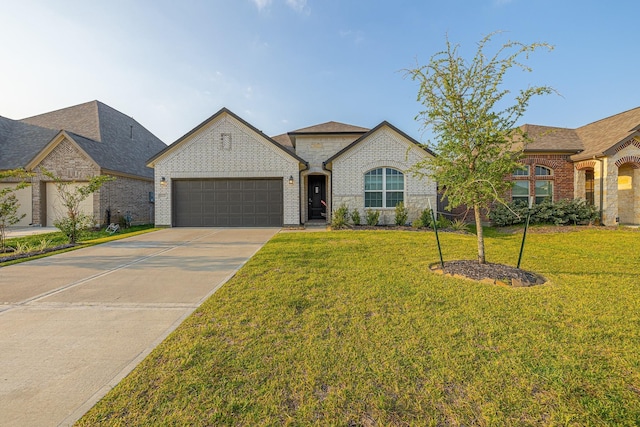 french country inspired facade with a front yard, concrete driveway, brick siding, and a garage