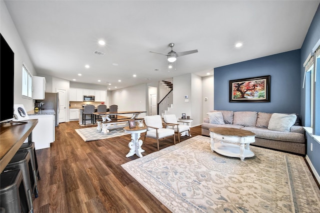 living room featuring dark wood-style floors, visible vents, recessed lighting, ceiling fan, and stairs